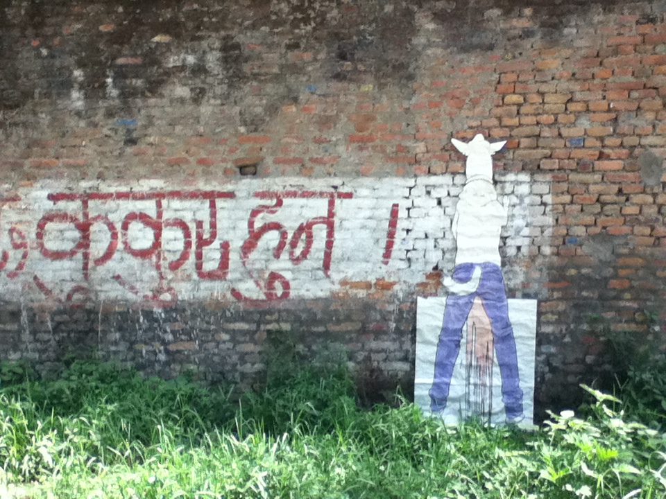 a wall with writing on it and a poster of a half-human-half-dog creature urinating